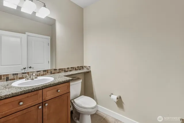 a bathroom with a granite countertop sink a toilet and a mirror