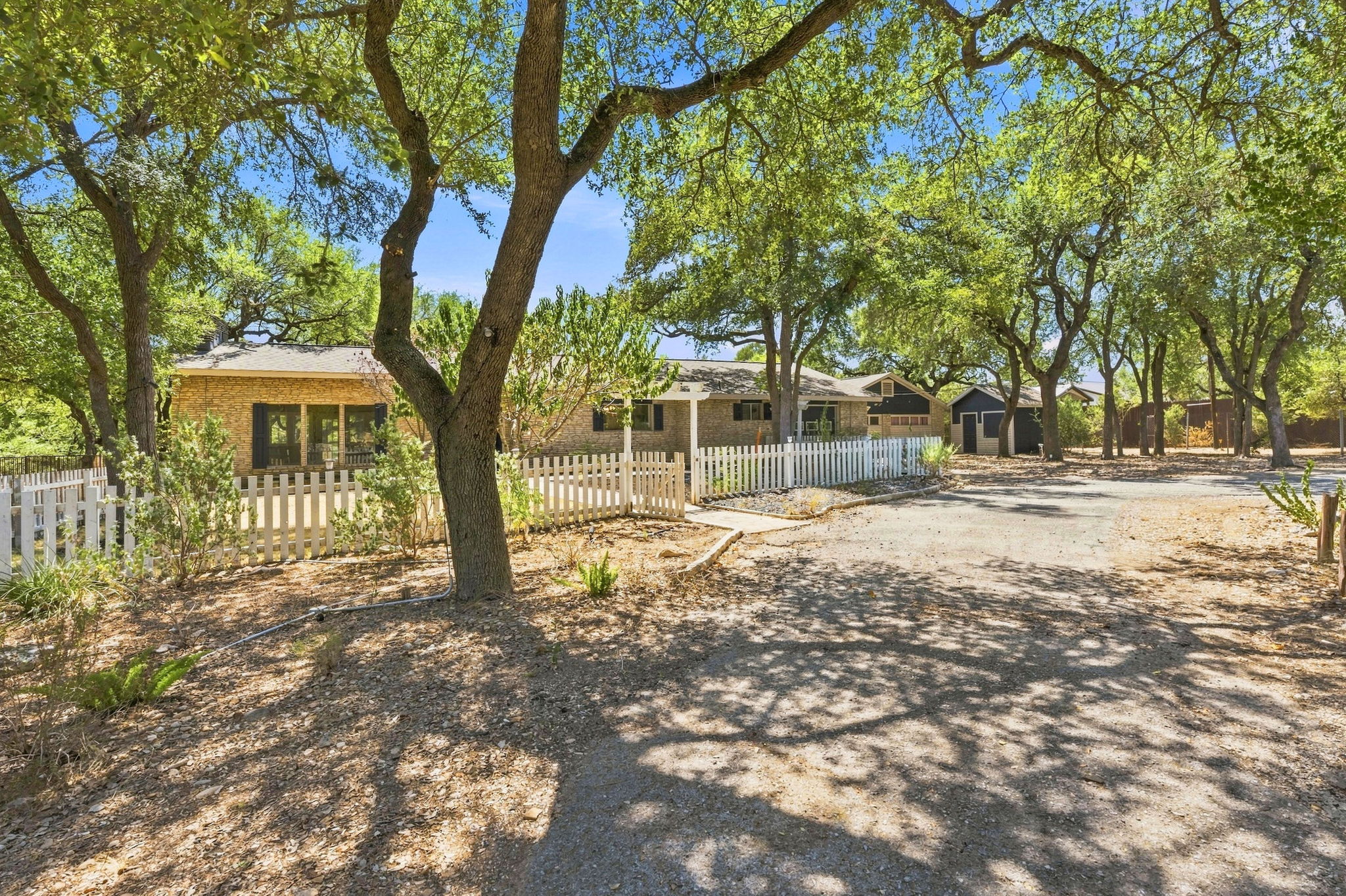 3809 Wyldwood Road Austin, TX 78739 - Photo 6 of 40 Mature oak trees shade the stone exterior and picket-fenced front yard of this single-level home.