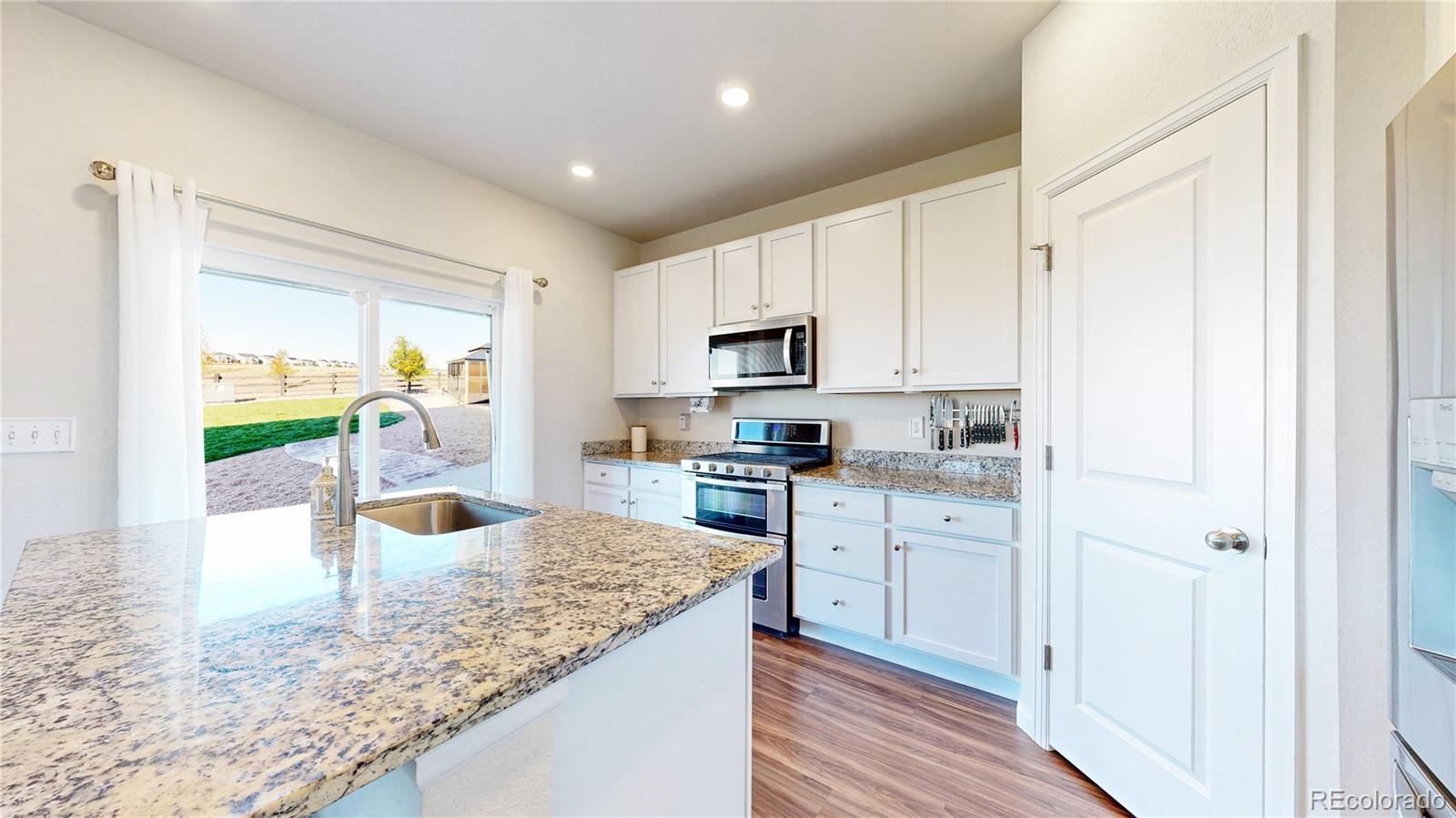 26709 East 1st Place Aurora, CO 80018 - Photo 13 of 50 a kitchen with stainless steel appliances granite countertop a refrigerator a stove and a sink with wooden floor