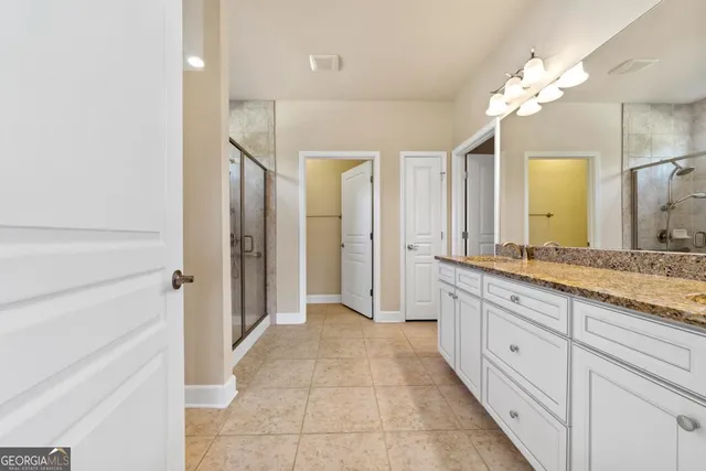 a bathroom with a granite countertop double vanity sink and a mirror