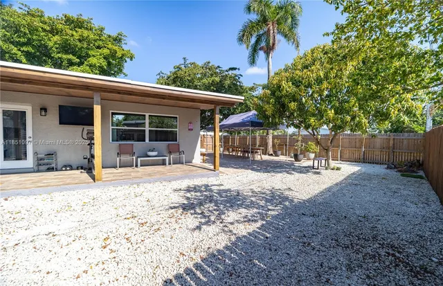 a view of a backyard with a table and chairs under a large tree