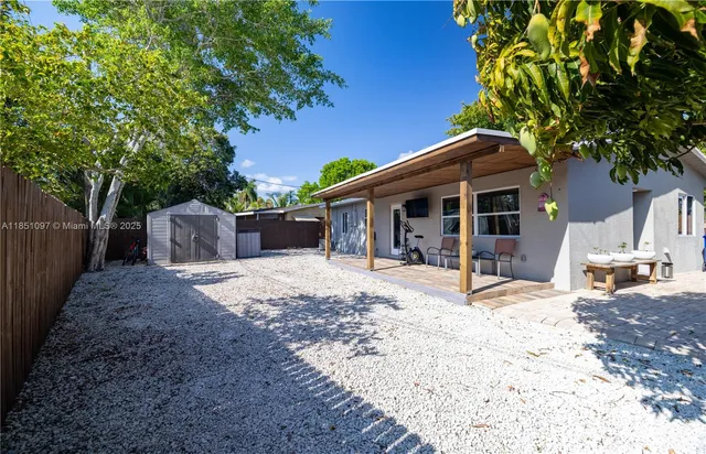 a patio table and chairs with potted plants and large tree