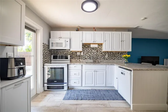 a kitchen with white cabinets and sink
