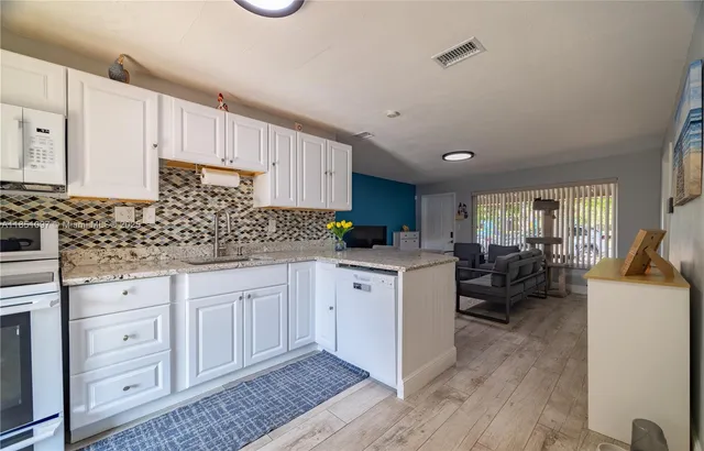 a kitchen with granite countertop white cabinets and white appliances