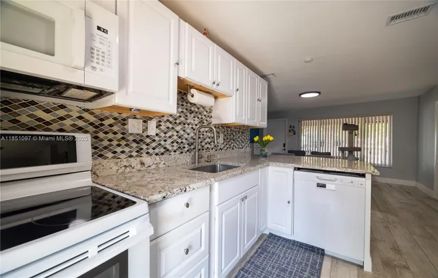 a kitchen with granite countertop a sink stove and cabinets