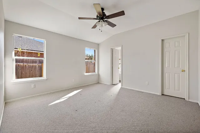 an empty room with windows and fan