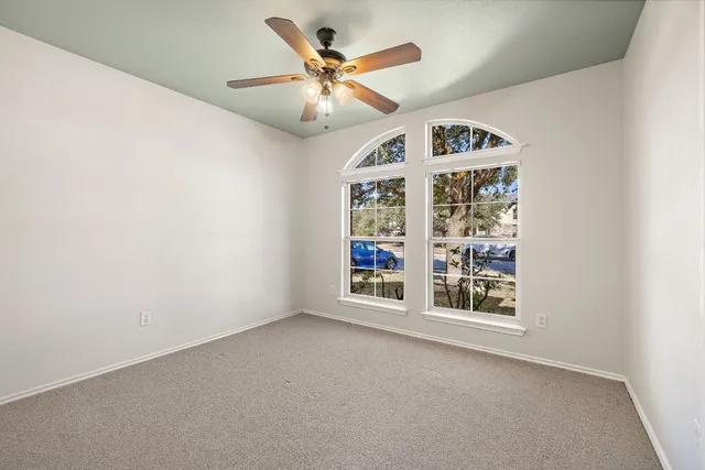 an empty room with windows and fan
