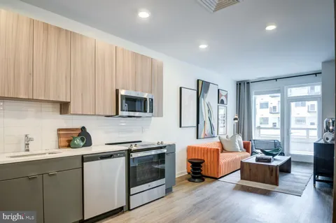a living room with stainless steel appliances furniture and a kitchen view
