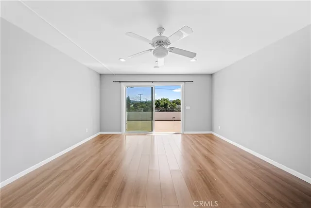 a view of an empty room with a window and wooden floor