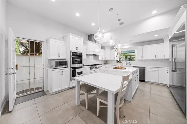 a large white kitchen with lots of counter space a sink appliances and cabinets