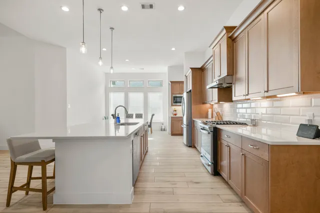 a kitchen with stainless steel appliances granite countertop a stove a sink and a refrigerator
