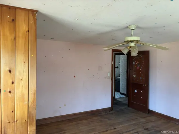 a view of a hallway to room with wooden floor and chandelier