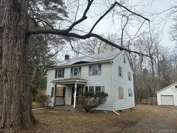 a view of a house with a yard and a large tree