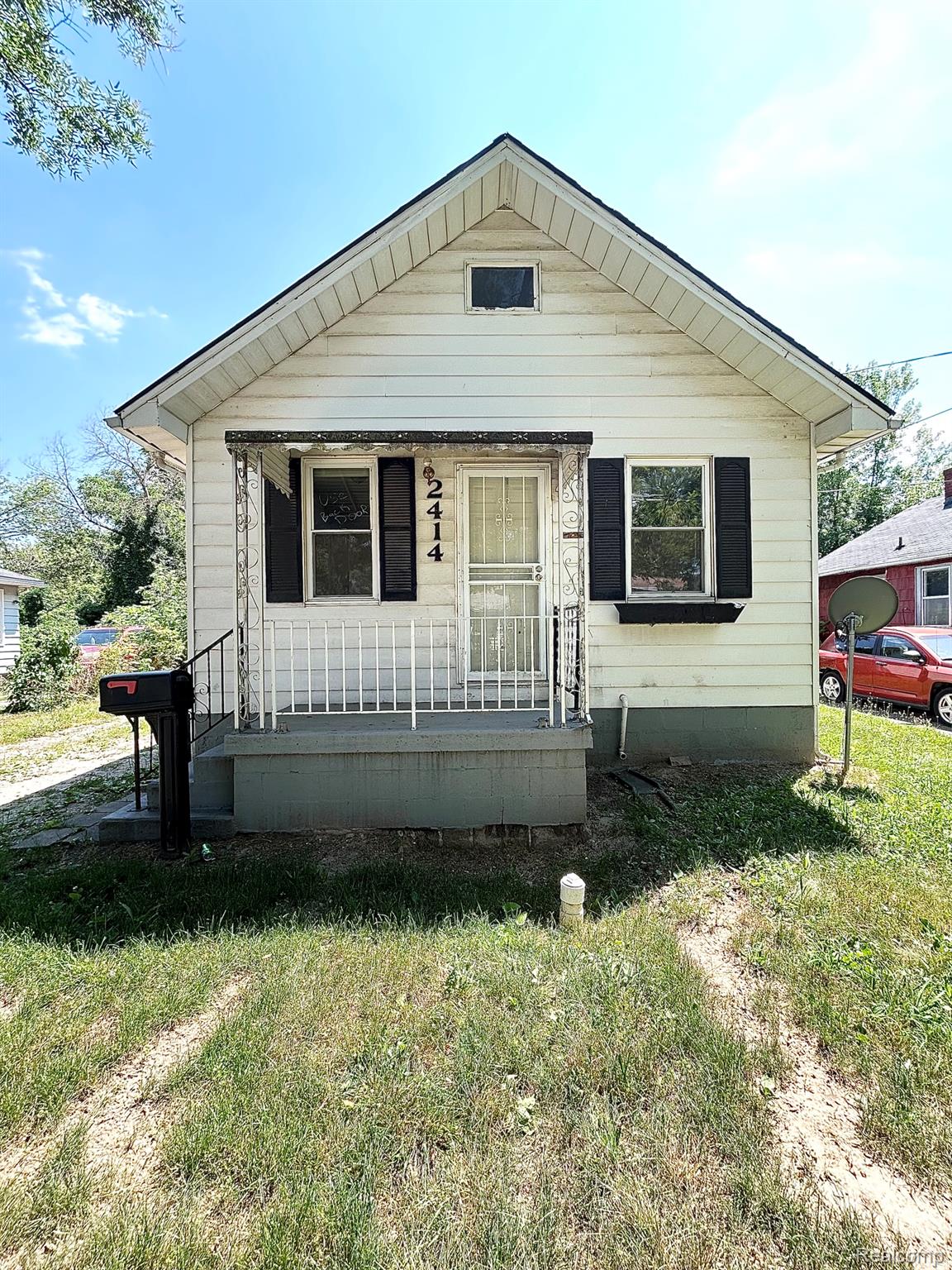 2414 Thom Street Flint, MI 48506 - Photo 1 of 8 White siding exterior featuring a covered front porch with wrought iron railing
