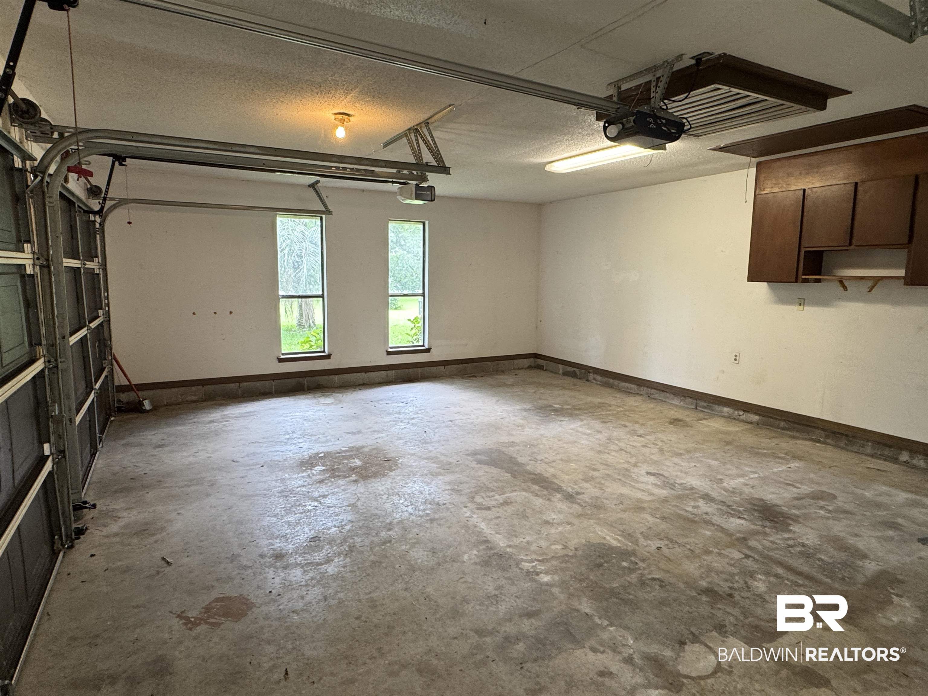 33370 Highway 98 Lillian, AL 36549 - Photo 39 of 58 Spacious garage with dual windows, wood-finish wall cabinets, fluorescent lighting, and a garage door opener system