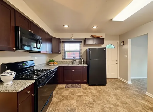 a kitchen with granite countertop a refrigerator a stove a microwave a sink and cabinets