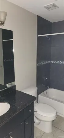 a bathroom with a granite countertop sink a toilet and a shower