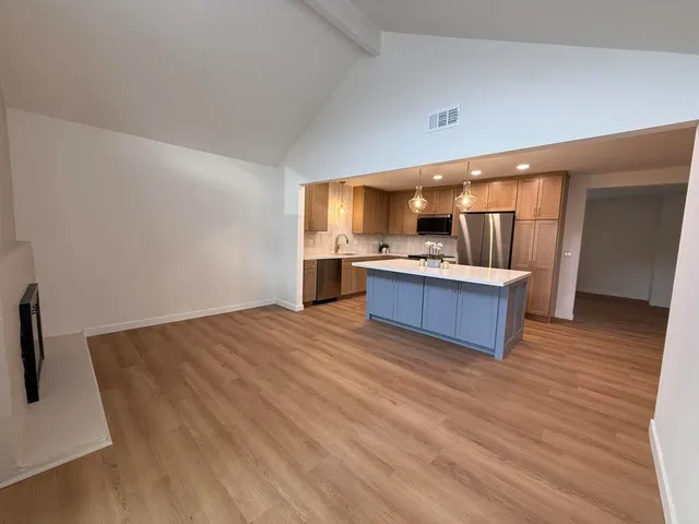 a kitchen with stainless steel appliances kitchen island wooden floors and granite counter top