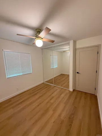 an empty room with wooden floor fan and windows