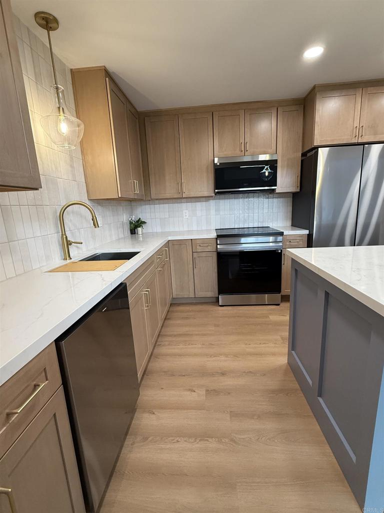 10296 Baroness Avenue San Diego, CA 92126 - Photo 8 of 27 a kitchen with stainless steel appliances a sink dishwasher a refrigerator a stove top oven a sink and dishwasher with wooden floor