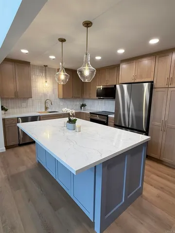 a kitchen with kitchen island a sink a stove a refrigerator and island with wooden floor