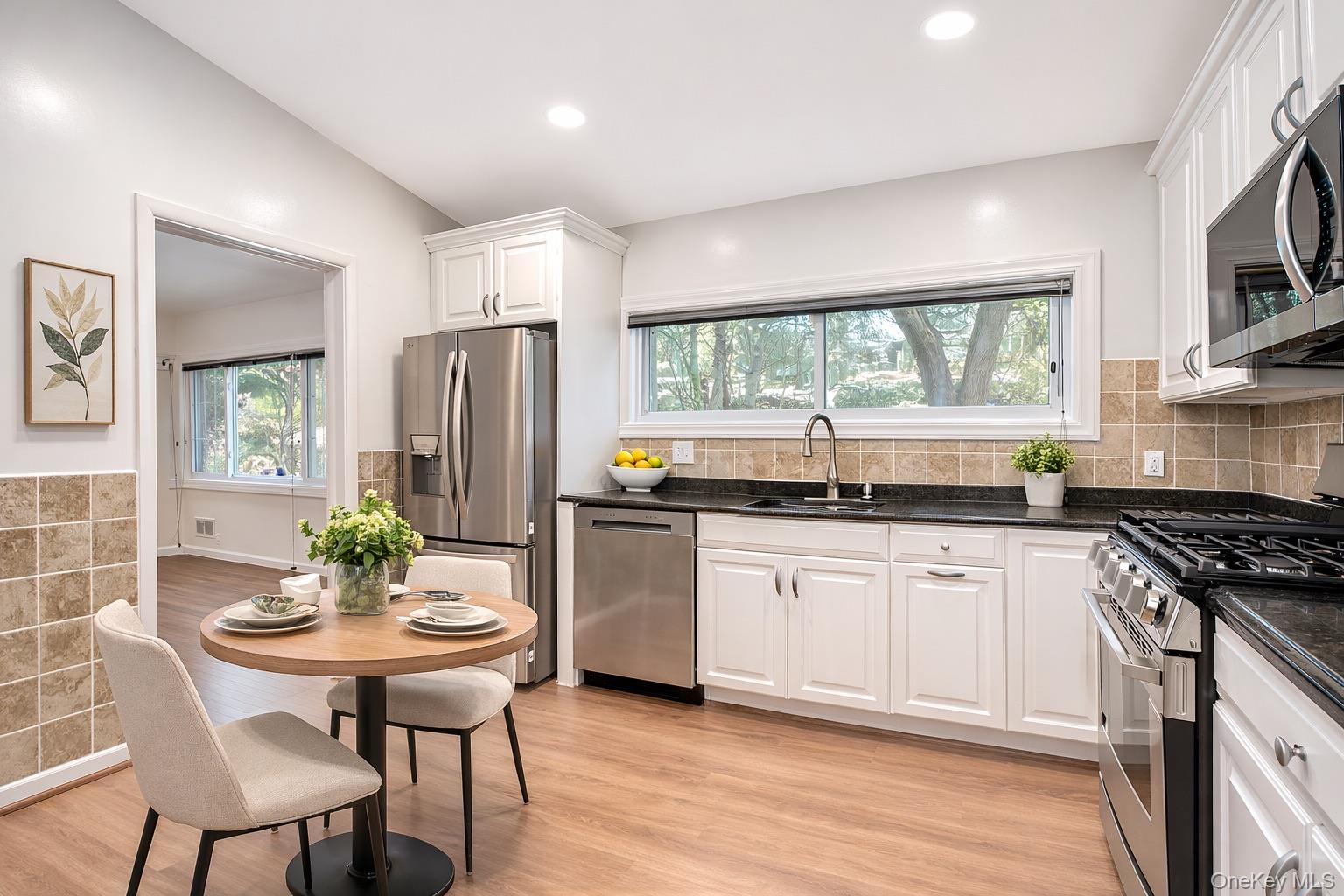 415 Pinebrook Boulevard New Rochelle, NY 10804 - Photo 8 of 20 a kitchen with stainless steel appliances granite countertop a stove a sink dishwasher a dining table and chairs with wooden floor