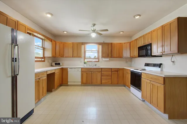 a large kitchen with cabinets a sink a window and stainless steel appliances