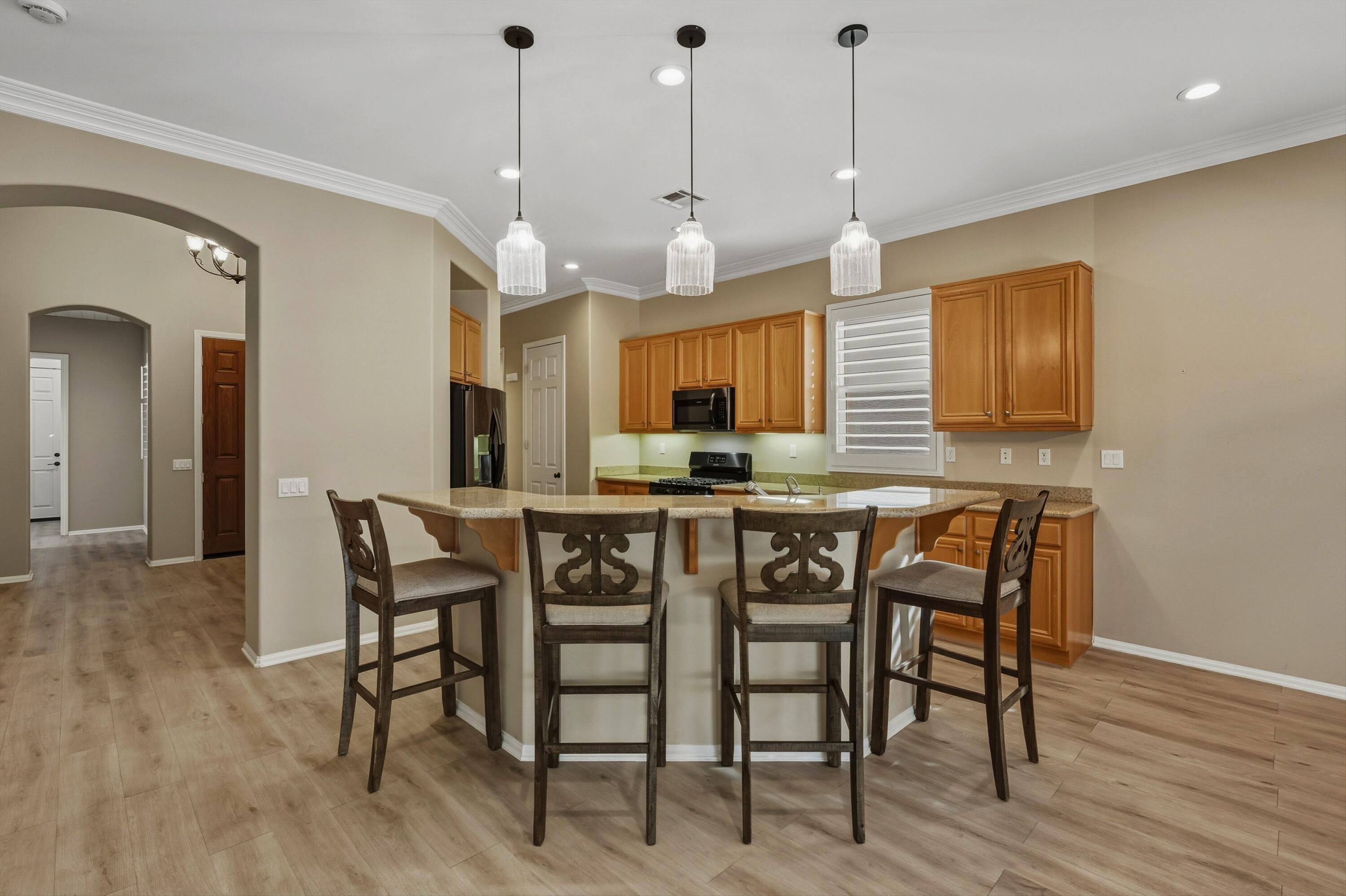 49465 Lewis Road Indio, CA 92201 - Photo 11 of 31 a kitchen with stainless steel appliances granite countertop wooden floor dining table and chairs