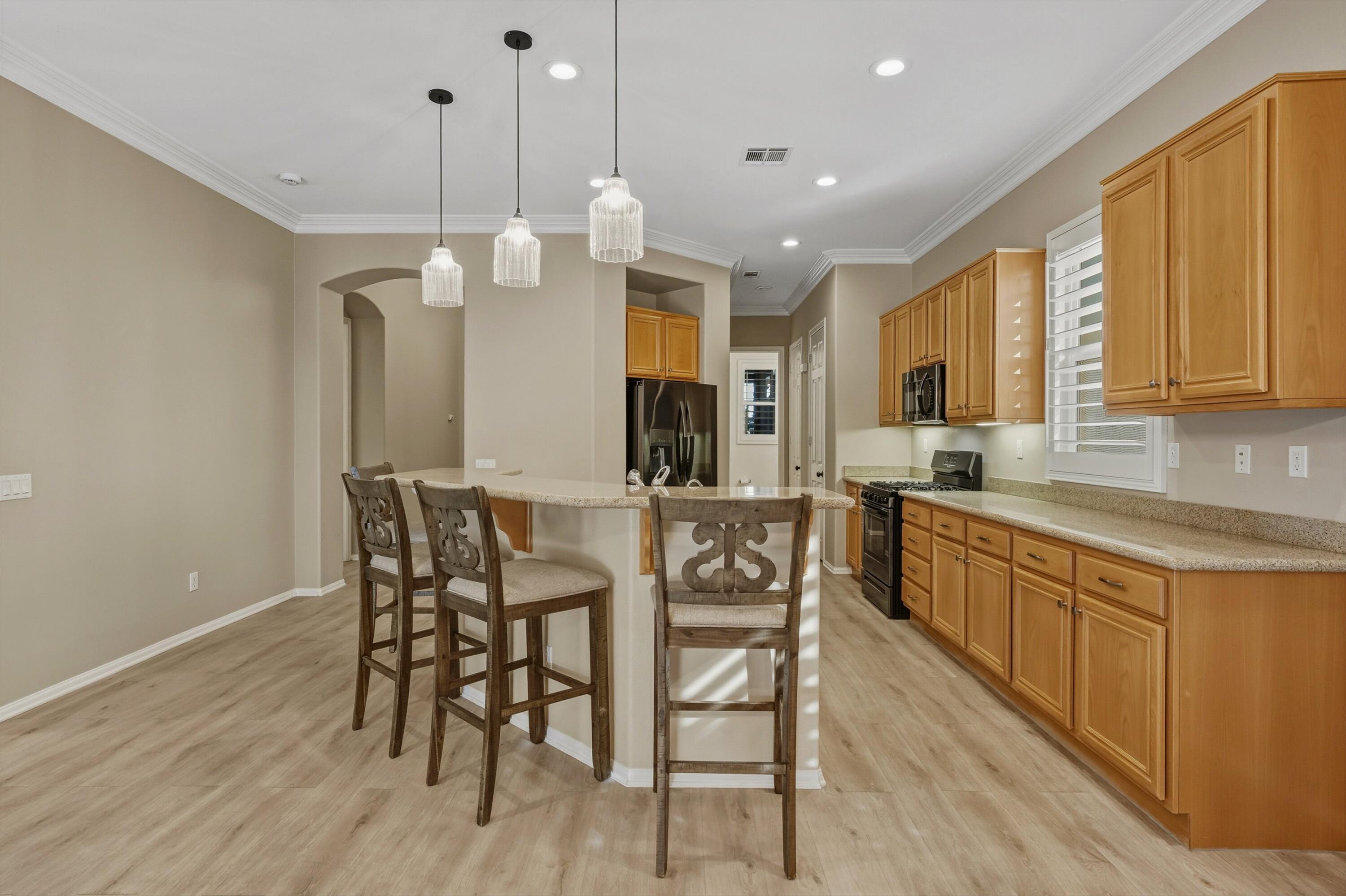 49465 Lewis Road Indio, CA 92201 - Photo 14 of 31 a kitchen with stainless steel appliances kitchen island granite countertop a table chairs and a wooden floor