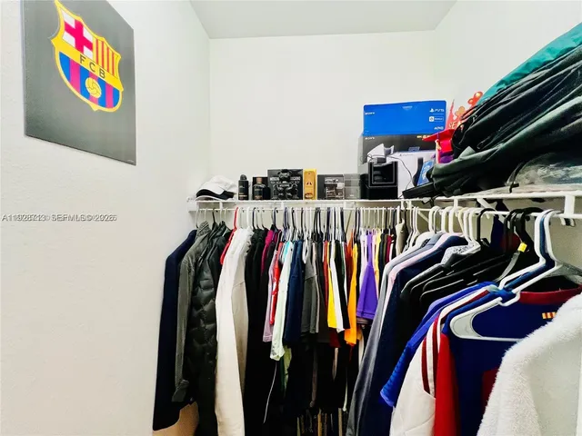 a view of walk in closet with clothes and shoes