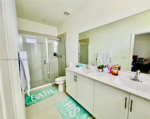 a bathroom with a double vanity sink toilet mirror and shower