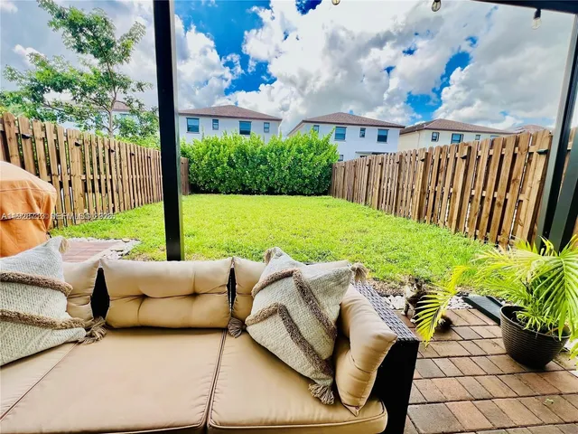 a backyard of a house with table and chairs plants and large tree