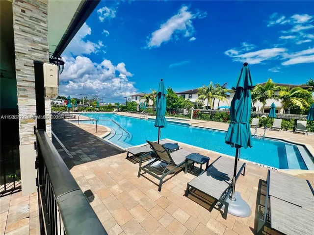 a view of a swimming pool with a patio and fire pit