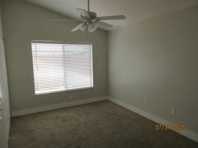 an empty room with a window and a fan