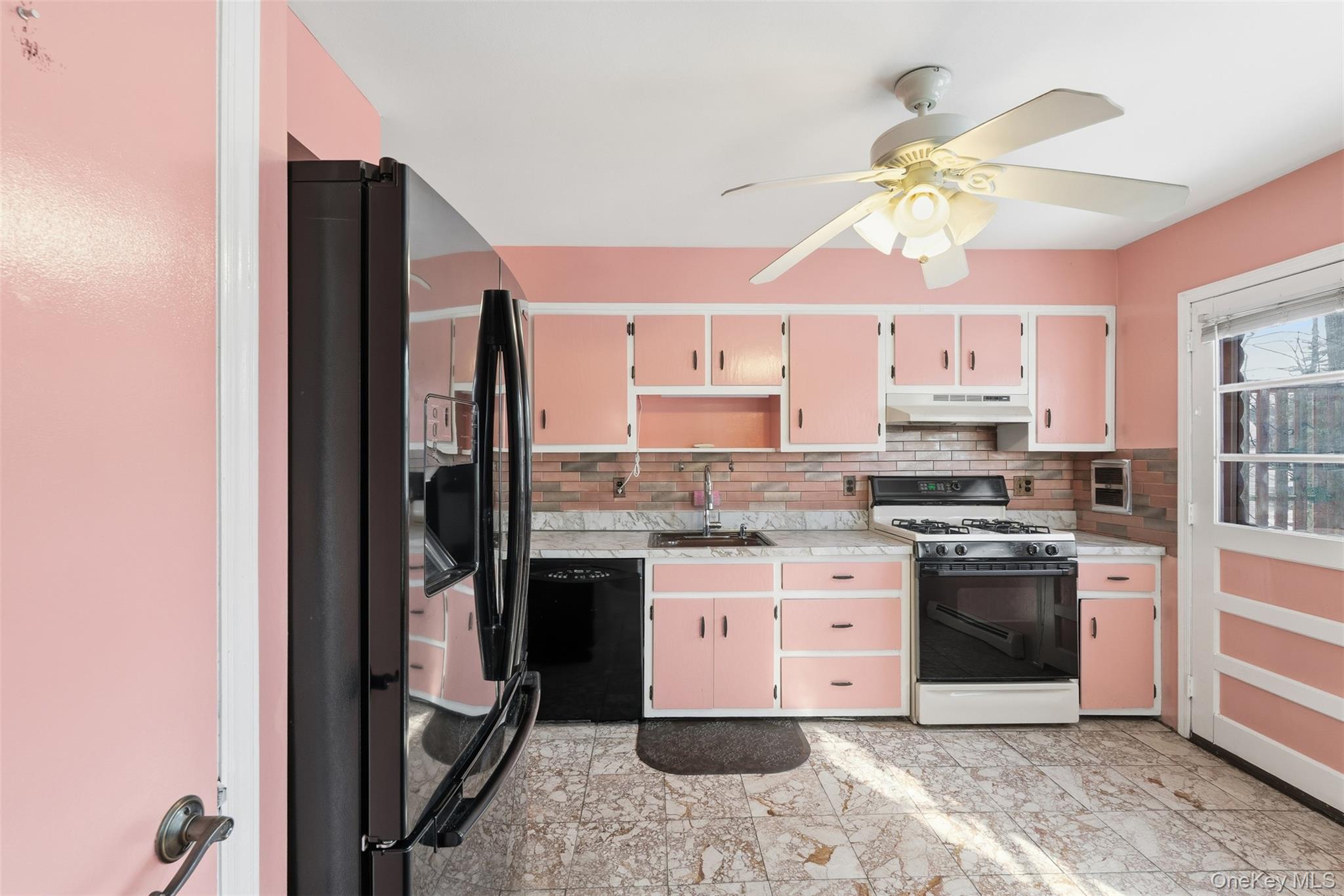 563 Union Road Spring Valley, NY 10977 - Photo 1 of 16 Kitchen featuring pink cabinetry with white trim, a black refrigerator, a black gas range, and a ceiling fan with integrated lighting