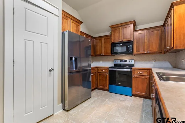 a kitchen with stainless steel appliances granite countertop a refrigerator stove and sink