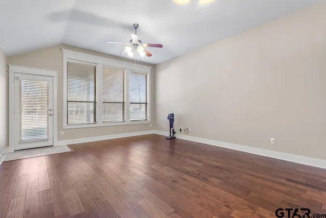 a view of an empty room with wooden floor and a window