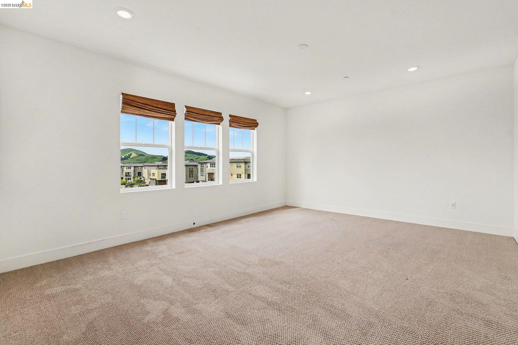 18210 Argento Loop San Ramon, CA 94583 - Photo 16 of 44 Spacious room featuring three large windows with woven wood shades, recessed lighting, and neutral carpeting