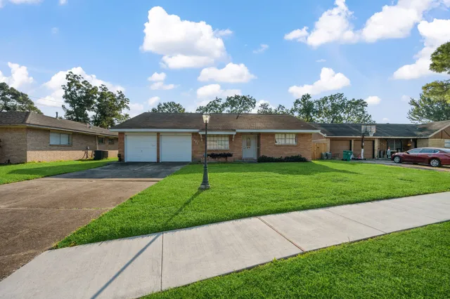 a view of a house next to a big yard and large trees