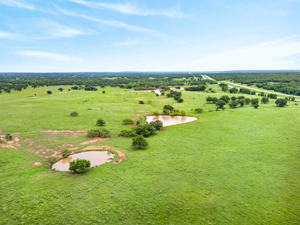 1080 North Greenbrier Road Nocona, TX 76255 - Photo 37 of 40 Expansive green landscape featuring multiple ponds, scattered mature trees, and a distant highway