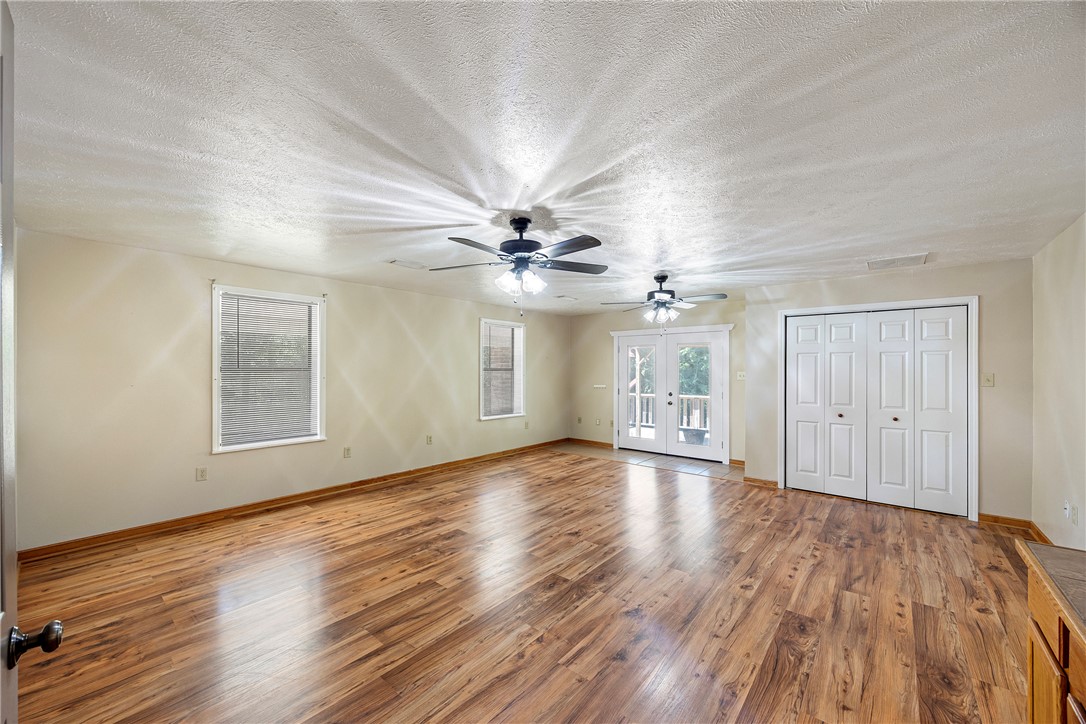 655 Charton Road Morrilton, AR 72110 - Photo 15 of 49 Spacious room featuring wood-finish flooring, two ceiling fans, dual windows with blinds, and double French doors opening to an exterior area