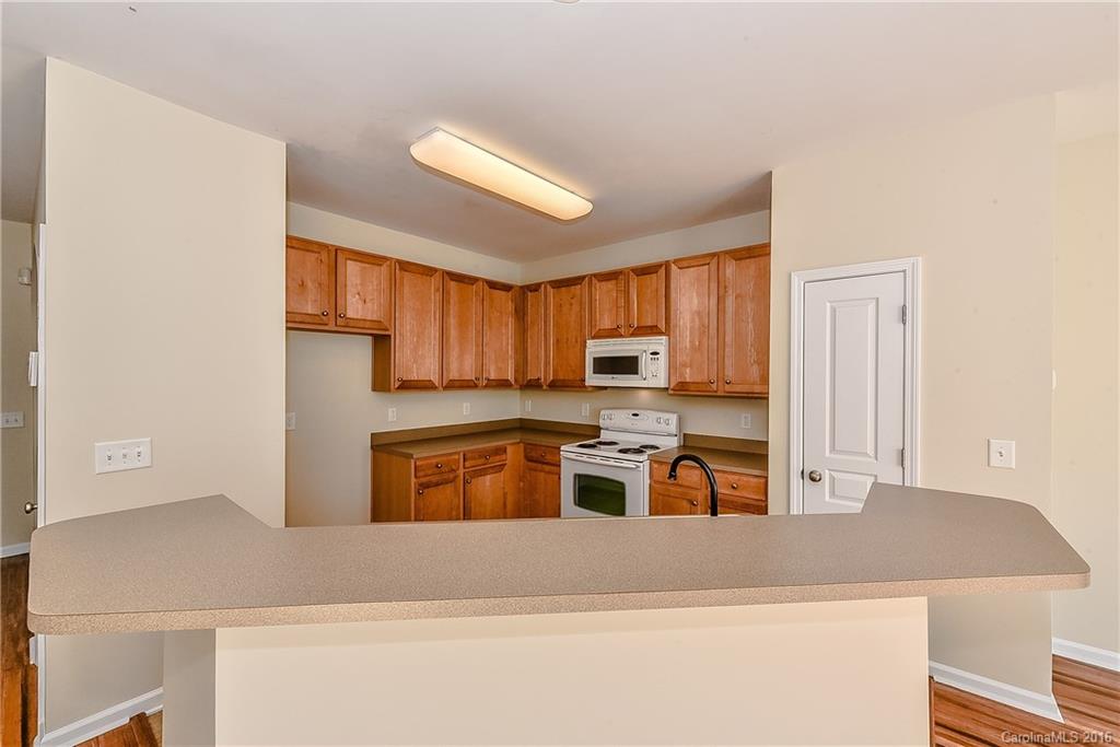 316 Sugar Ridge Court, Unit 95 Fort Mill, SC 29708 - Photo 10 of 23 a kitchen with stainless steel appliances granite countertop a stove top oven a sink a refrigerator white cabinets and wooden floor