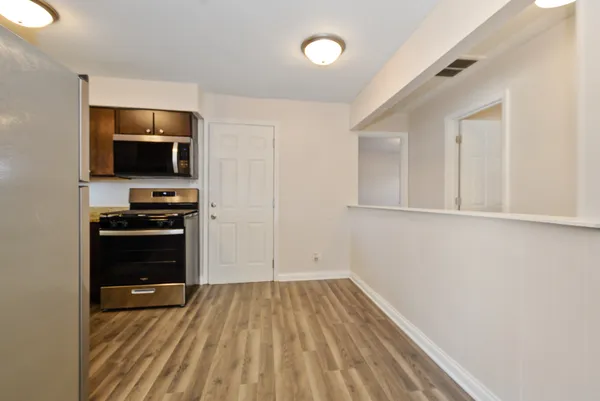 a view of kitchen and empty room with wooden floor