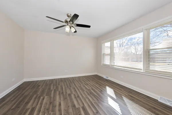 a view of empty room with wooden floor and fan