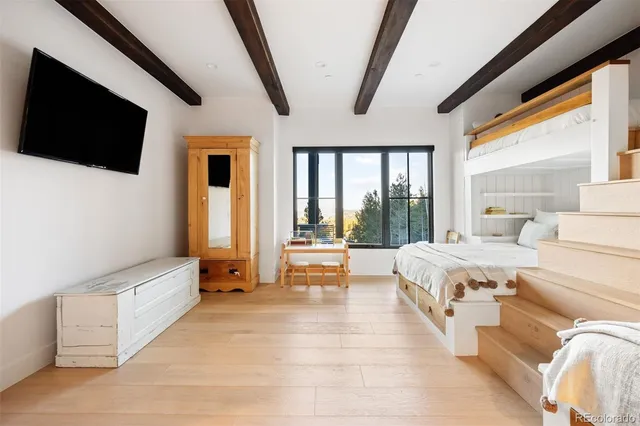 a spacious bedroom with a large bed and a flat tv screen