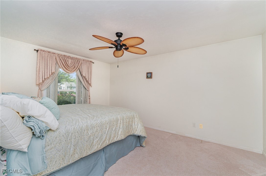 10615 Roxbury Court Lehigh Acres, FL 33936 - Photo 14 of 33 a bedroom with a bed and a chandelier