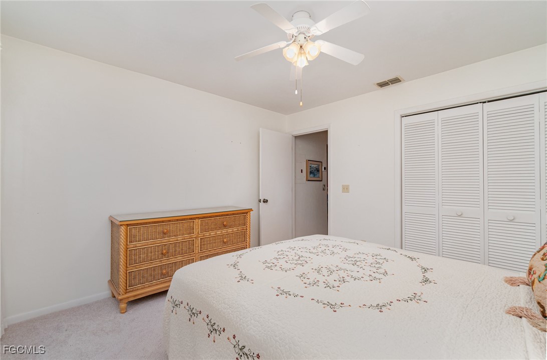 10615 Roxbury Court Lehigh Acres, FL 33936 - Photo 19 of 33 a bedroom with a bed dresser and a chandelier