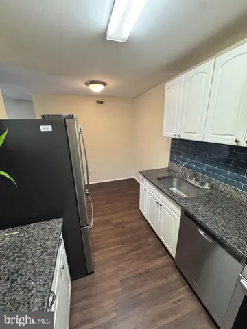 a kitchen with granite countertop a sink stove and cabinets