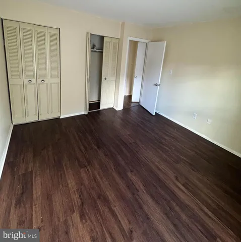 a view of an empty room with wooden floor and closet