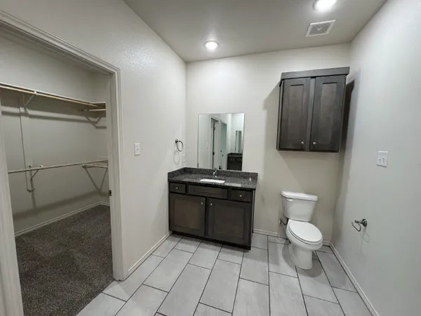 a spacious bathroom with a toilet a sink and a mirror